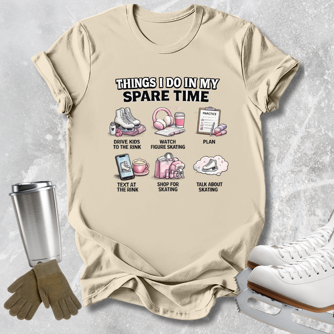 A beige graphic t-shirt laid flat on a light gray textured background, surrounded by ice skating props including white ice skates, gloves, and a metal tumbler. The t-shirt features a humorous graphic titled 'THINGS I DO IN MY SPARE TIME' with small illustrations and text for activities like driving kids to the rink, watching figure skating, planning, texting at the rink, shopping for skating, and talking about skating.