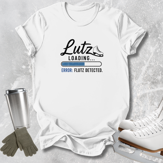 A white graphic T-shirt laid flat on a light gray textured surface, with a printed design reading 'Lutz Loading.