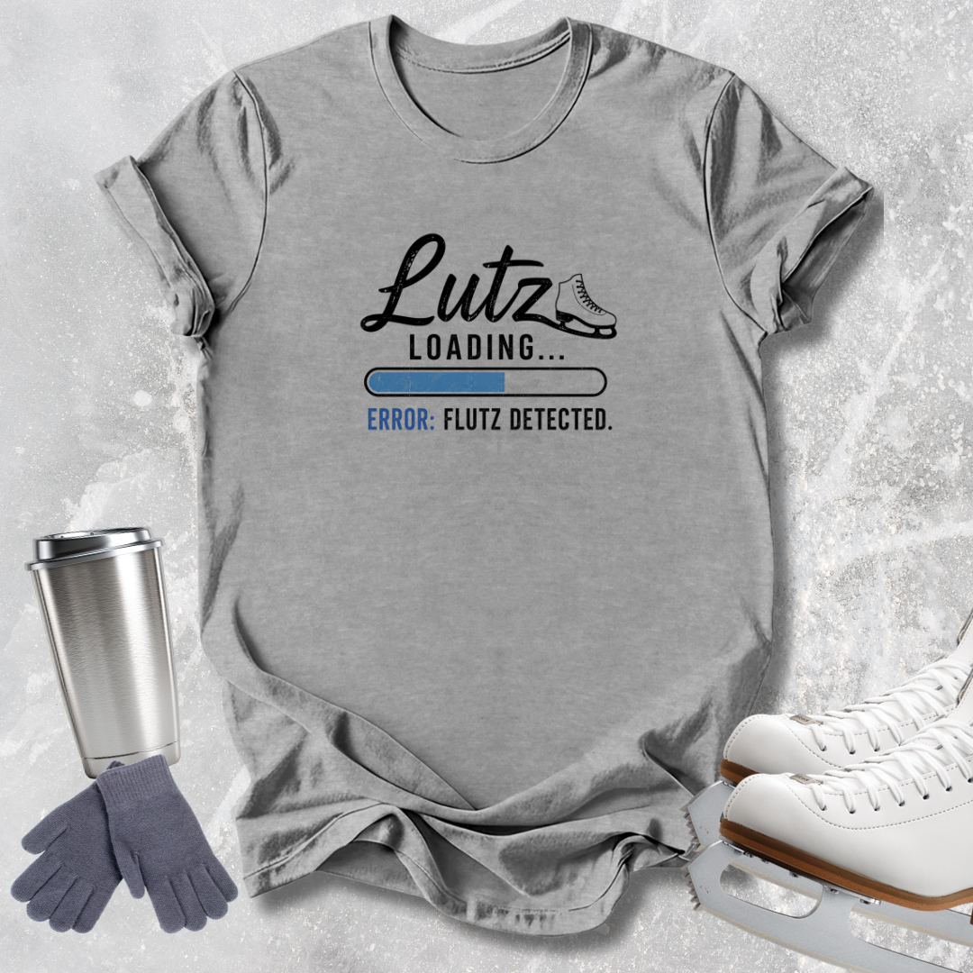 A heather gray graphic T-shirt laid flat on a light textured surface, with a printed design reading 'Lutz Loading.
