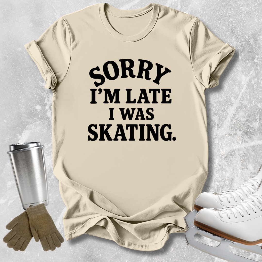 A beige graphic t-shirt with the text 'SORRY I'M LATE I WAS SKATING.' printed in black.