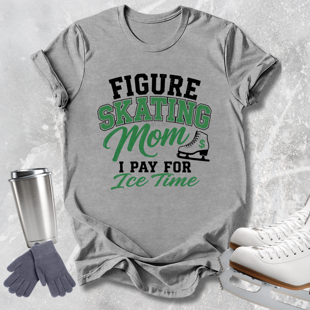 A heather gray graphic t-shirt featuring the text 'FIGURE SKATING Mom I PAY FOR Ice Time' in black and green, styled in a flat-lay with ice skates, a travel tumbler, and gloves on a textured light gray background.