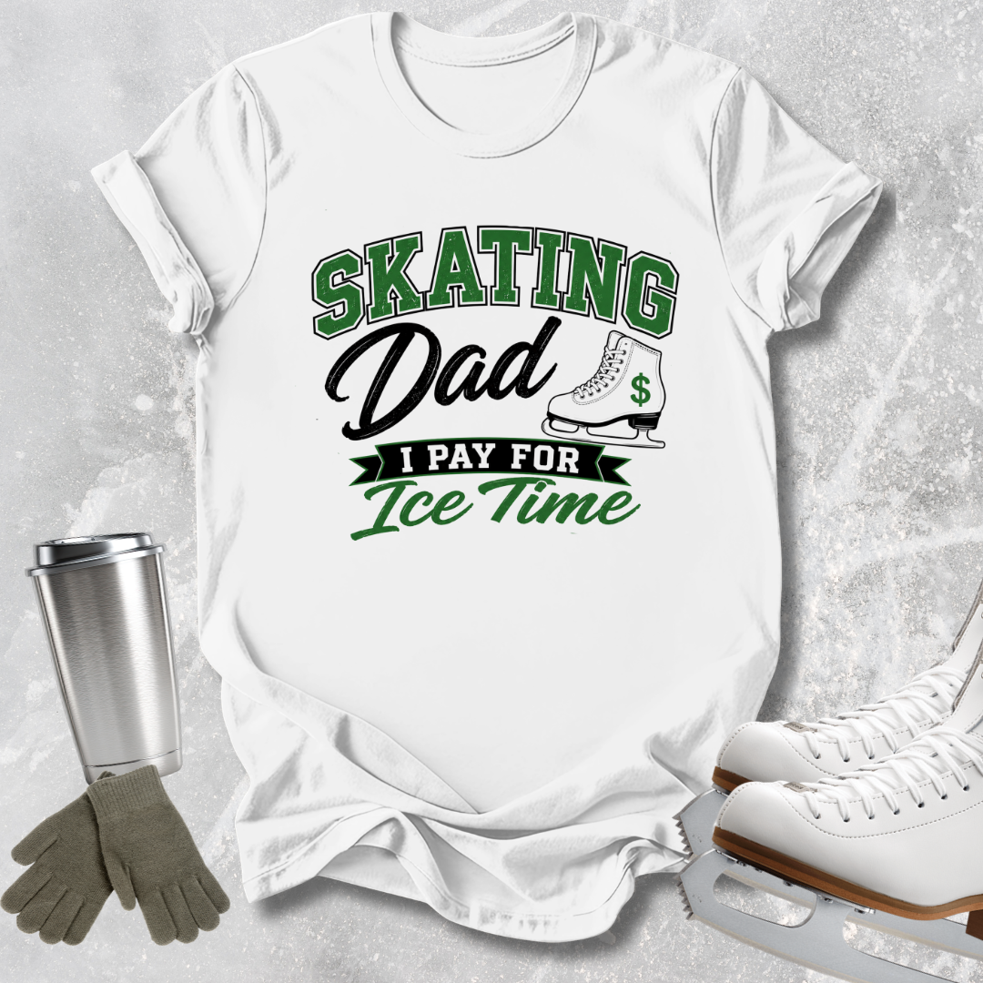 A white graphic t-shirt featuring the text 'SKATING Dad I PAY FOR Ice Time' in green and black, styled in a flat-lay with ice skates, gloves, and a metal tumbler on a gray textured background.