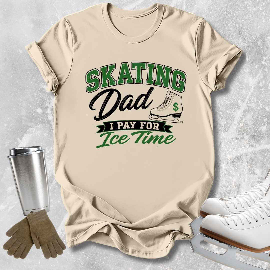 A beige graphic t-shirt featuring the text 'SKATING Dad I PAY FOR Ice Time' in green and black, styled in a flat lay with ice skates, gloves, and a travel tumbler on a gray textured background.
