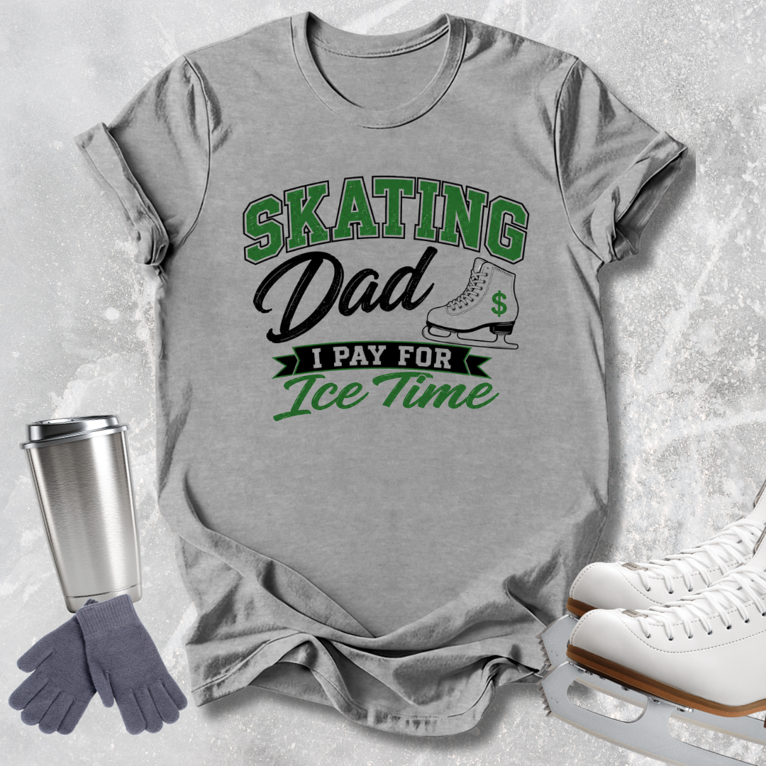 A heather gray graphic t-shirt featuring the text 'SKATING Dad I PAY FOR Ice Time' in green and black, styled in a flat-lay with ice skates, a travel tumbler, and gloves on a light gray textured background.