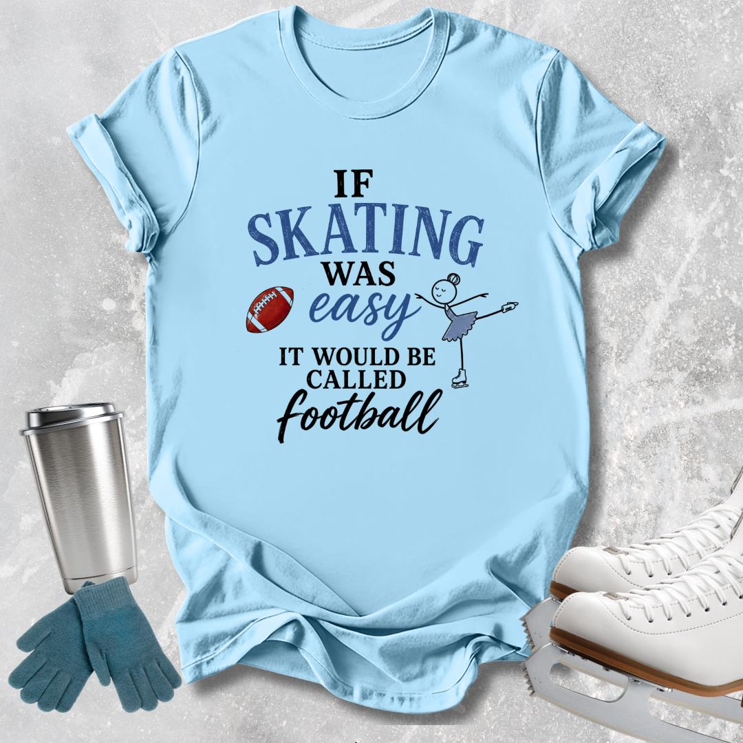 A light blue graphic t-shirt laid flat on a textured gray background, styled with ice skates, gloves, and a metal tumbler. The t-shirt features a dark blue and black text graphic that reads 'IF SKATING WAS easy IT WOULD BE CALLED Football' alongside a small illustration of a figure skater and a football.