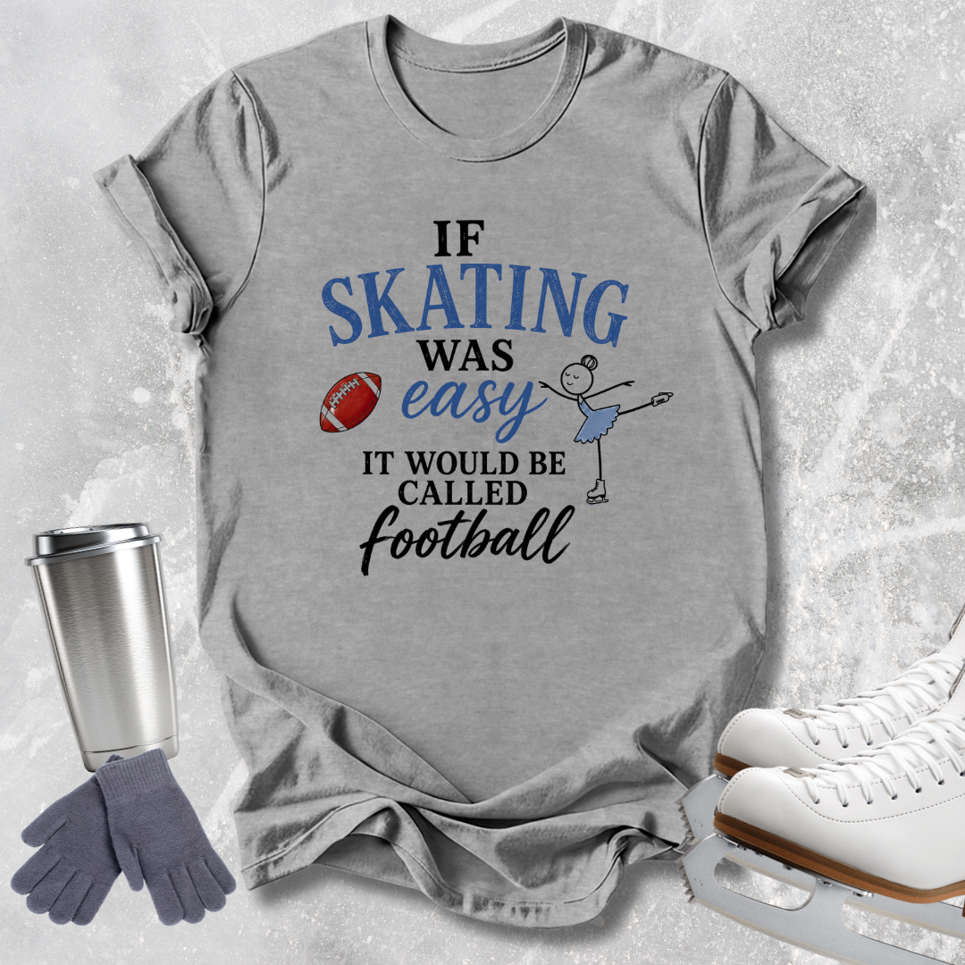 A heather gray graphic t-shirt laid flat on a light gray textured background, featuring the text 'IF SKATING WAS easy IT WOULD BE CALLED Football' in blue and black lettering, with a small stick-figure skater and football graphic. Surrounding props include a silver travel mug, gray gloves, and white ice skates.
