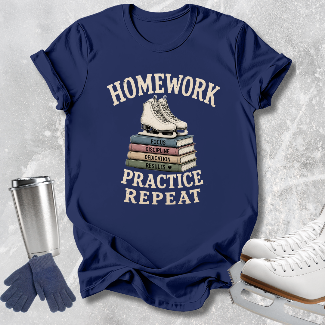 A navy blue graphic T-shirt laid flat on a light gray textured surface, featuring the words 'HOMEWORK PRACTICE REPEAT' in cream around an illustration of white ice skates stacked on books. A stainless steel tumbler, blue gloves, and white ice skates are arranged around the shirt as styled props.