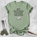 A sage green graphic t-shirt featuring the text 'MY SAVINGS FIGURE SKATES.' in black block letters above an illustration of white figure skates.