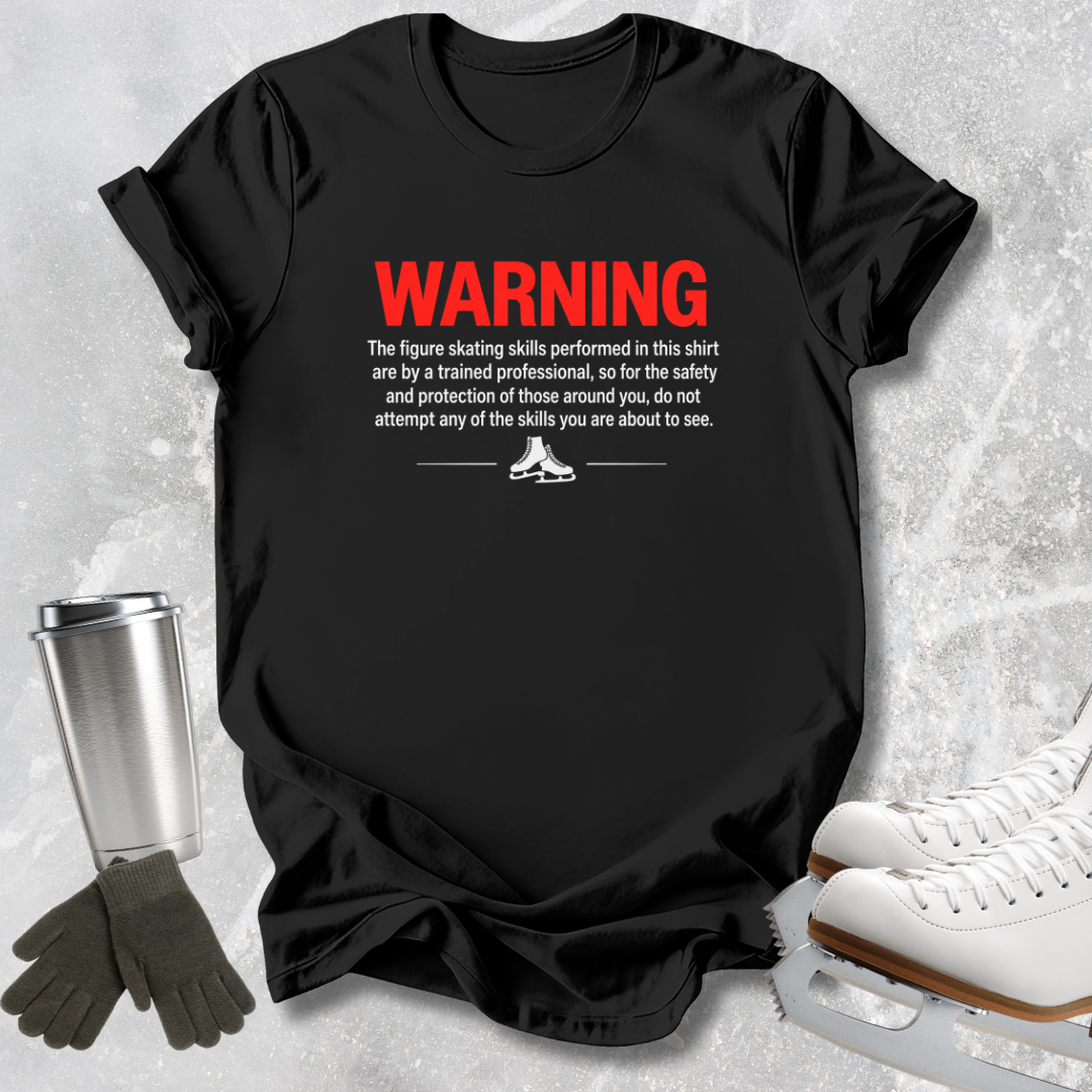 A black graphic t-shirt laid flat on a light gray textured background, styled with ice skates, gloves, and a metal cup. The shirt features a humorous warning label printed in red and white text.