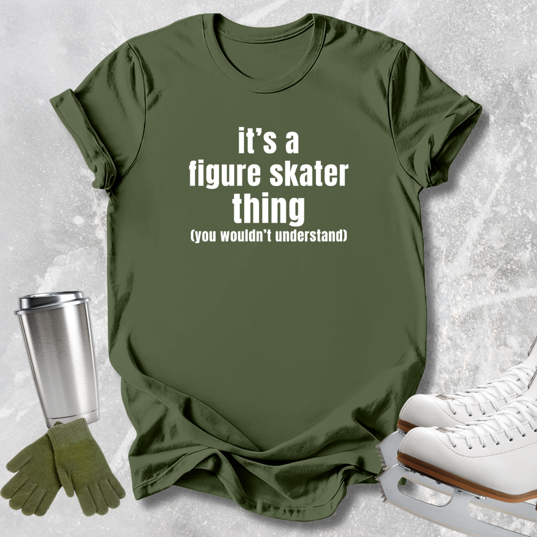An olive green graphic t-shirt with the text 'it's a figure skater thing (you wouldn't understand)' in white, styled in a flat-lay with white ice skates, a silver travel mug, and green gloves on a textured gray background.