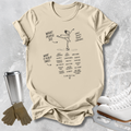 A beige graphic t-shirt featuring a black line art illustration of an ice dancer with text, styled in a flat-lay with ice skates, gloves, and a travel mug on a textured gray background.