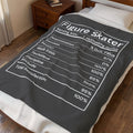 A dark gray blanket with a white nutrition label design printed on it, styled on a bed in a bedroom setting.